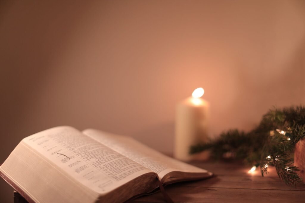 An open Bible resting beside warm candlelight, illustrating quiet morning reflection in God's Word